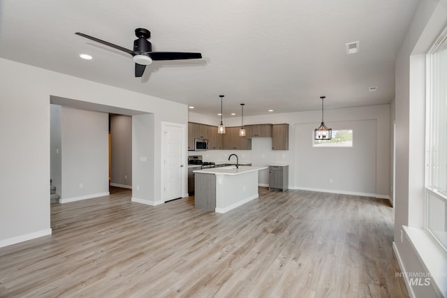 unfurnished living room featuring light wood-type flooring, ceiling fan, and sink