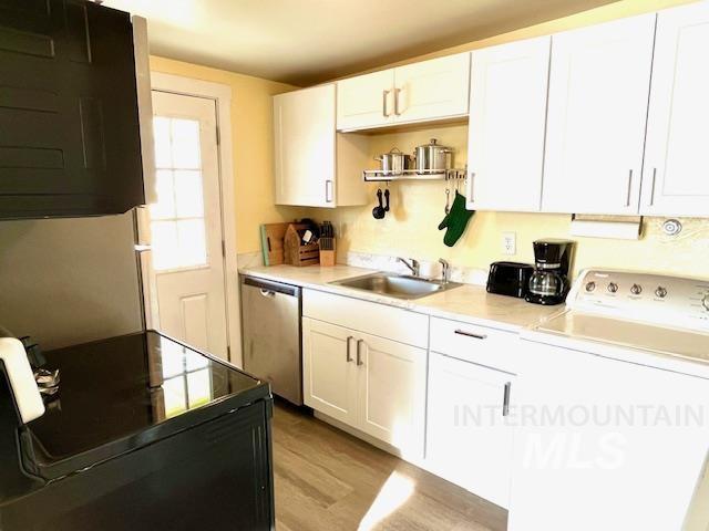 kitchen with washer / clothes dryer, white cabinetry, sink, and stainless steel dishwasher