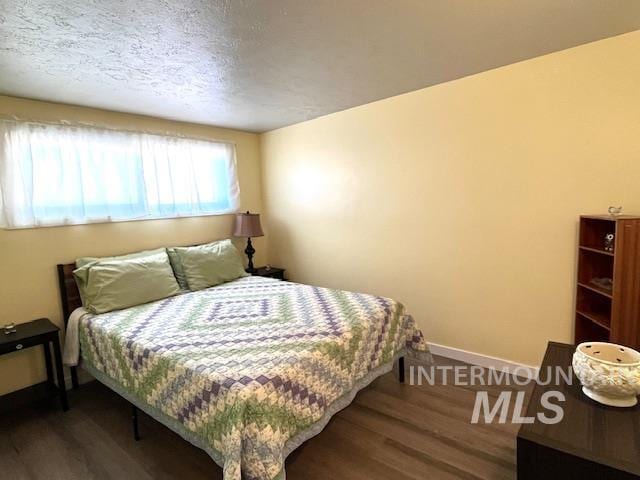 bedroom featuring a textured ceiling and dark hardwood / wood-style flooring