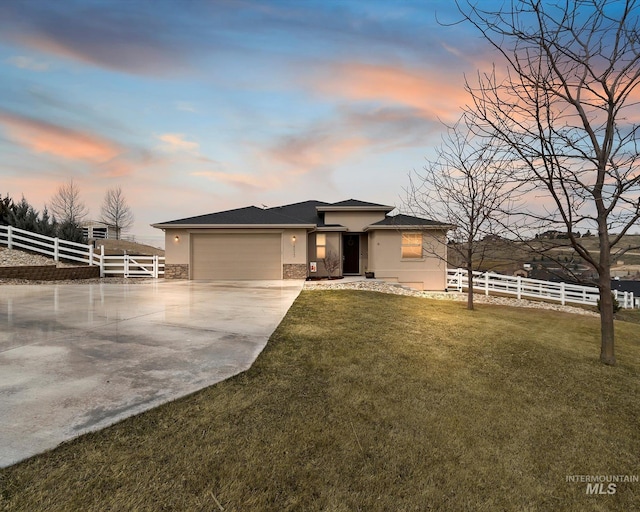 view of front of home with stucco siding, driveway, a front lawn, and fence