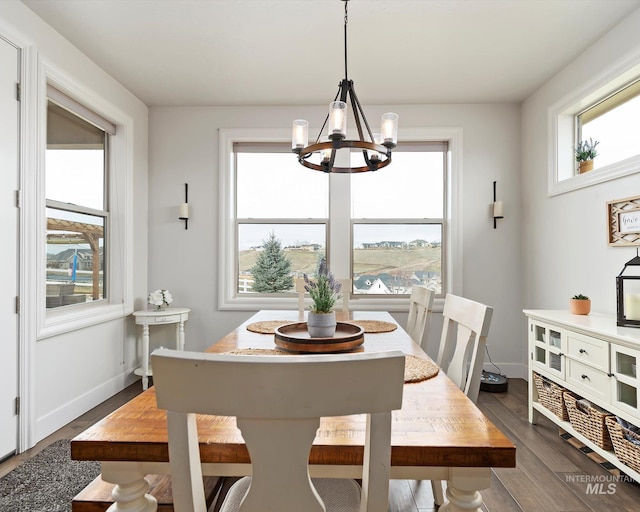 dining space with an inviting chandelier, baseboards, and dark wood-style flooring