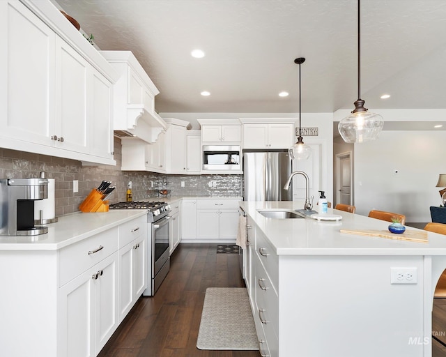 kitchen featuring white cabinetry, backsplash, appliances with stainless steel finishes, and a sink