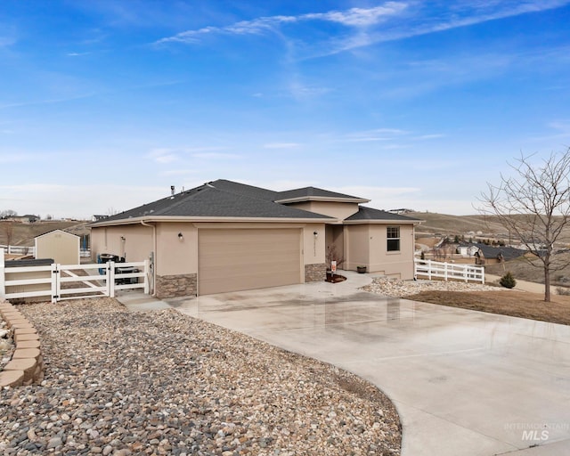 view of front of house featuring stucco siding, driveway, a gate, stone siding, and fence