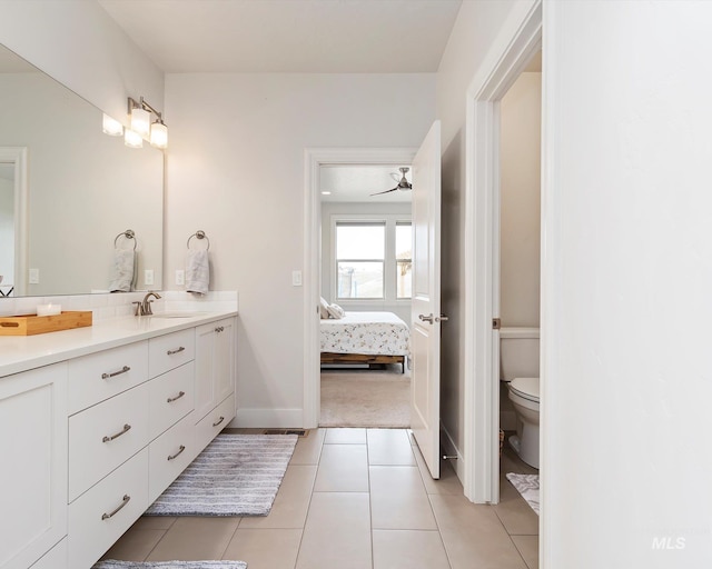 ensuite bathroom with toilet, ensuite bath, tile patterned flooring, baseboards, and vanity