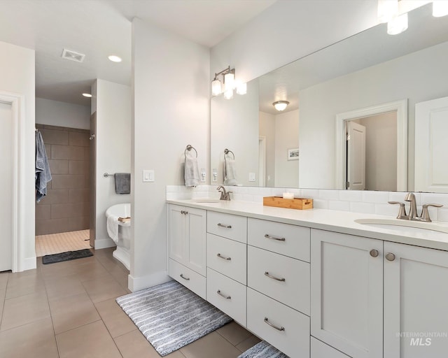 full bath featuring tile patterned flooring, double vanity, tasteful backsplash, and a sink