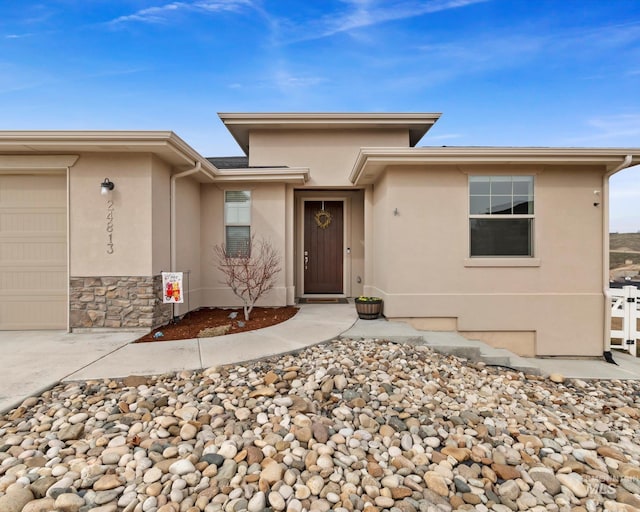 view of front of house featuring stone siding, stucco siding, and a garage