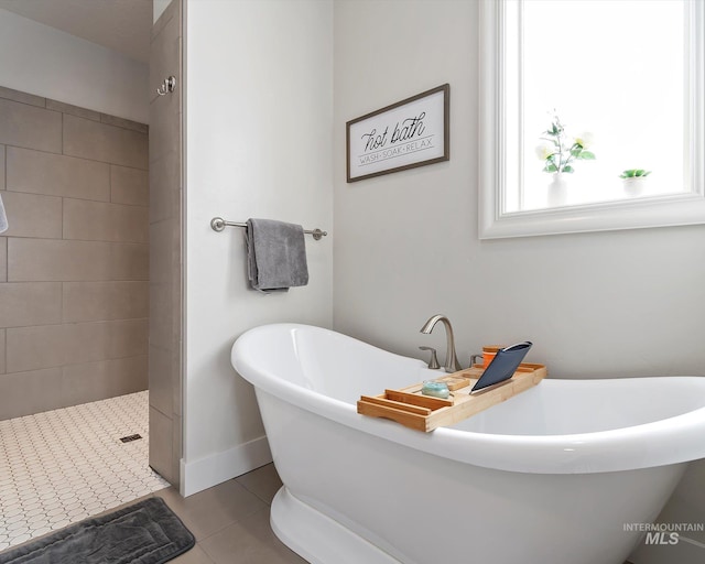 bathroom featuring tile patterned floors, tiled shower, baseboards, and a freestanding tub