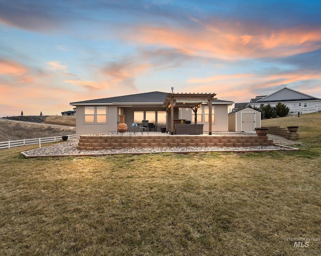 back of property at dusk featuring fence, a shed, an outdoor structure, a pergola, and a patio