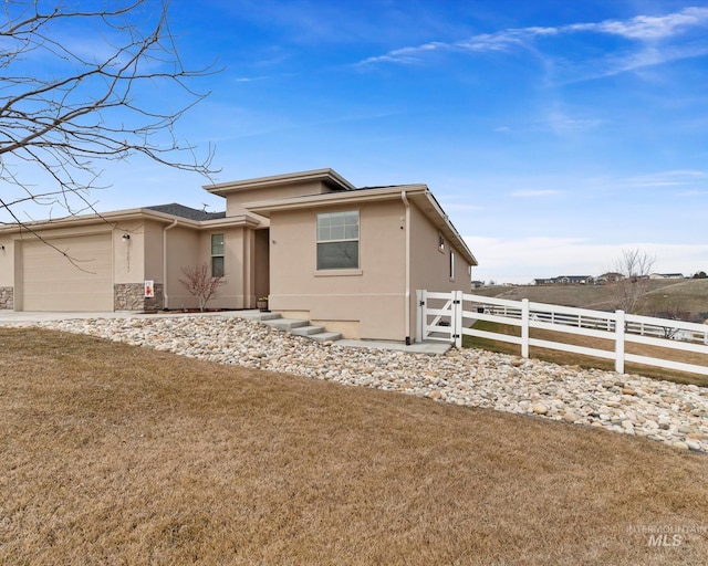 view of front of property featuring stucco siding, a front yard, a garage, and fence