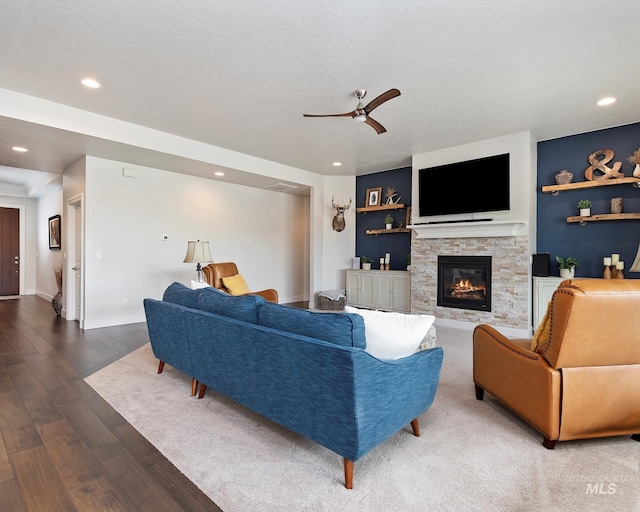 living room featuring ceiling fan, recessed lighting, a fireplace, wood finished floors, and a textured ceiling