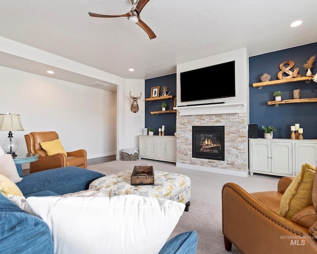 living area featuring visible vents, carpet floors, recessed lighting, ceiling fan, and a stone fireplace