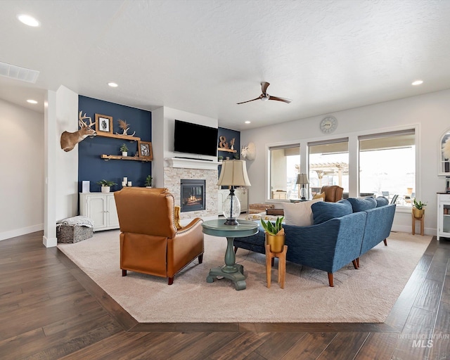 living area with dark wood-style floors, visible vents, recessed lighting, and a fireplace