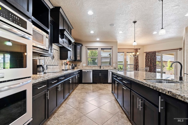 4315 N Nuova Ave, Meridian, ID 83646 - kitchen featuring light stone counters, tasteful backsplash, hanging light fixtures, appliances with stainless steel finishes, and a sink