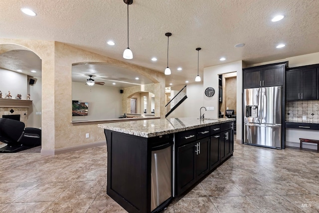 4315 N Nuova Ave, Meridian, ID 83646 - kitchen featuring stainless steel fridge, arched walkways, an island with sink, open floor plan, and a sink