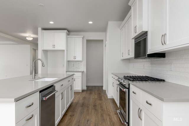 kitchen with white cabinets, light countertops, stainless steel appliances, dark wood-type flooring, and a sink