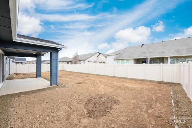 view of yard featuring a patio, a fenced backyard, and a residential view