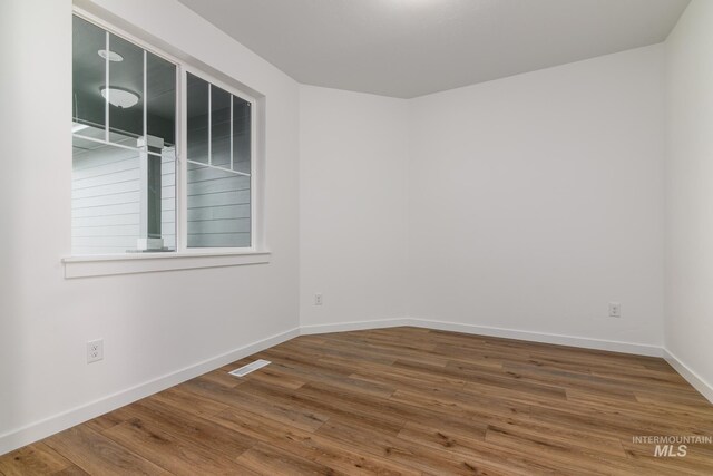 unfurnished room with baseboards, visible vents, and wood finished floors