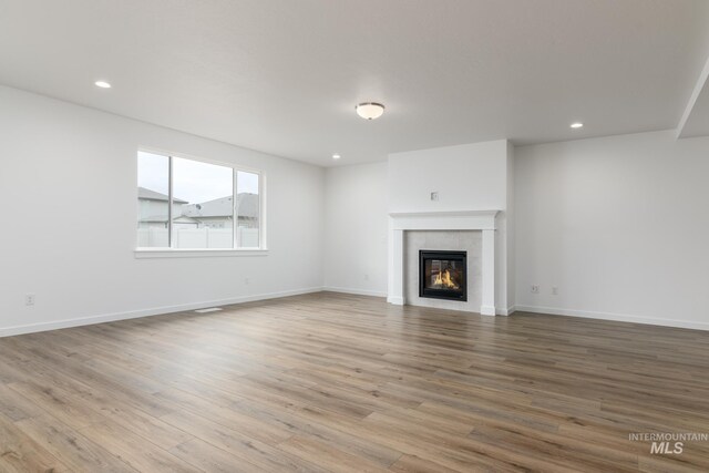 unfurnished living room with baseboards, a fireplace, wood finished floors, and recessed lighting