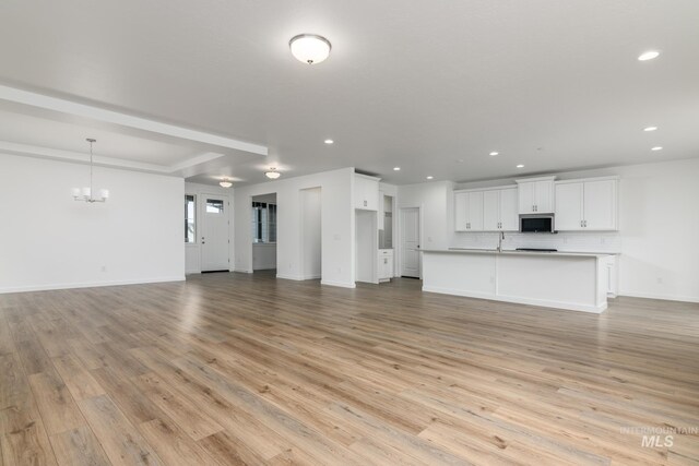unfurnished living room featuring baseboards, light wood-style floors, a chandelier, and recessed lighting
