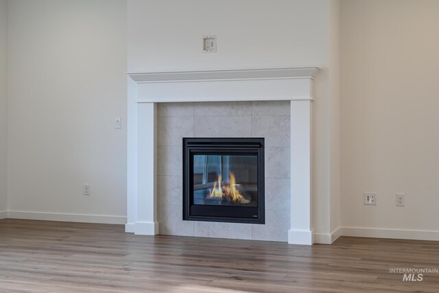 room details featuring baseboards, wood finished floors, and a tiled fireplace