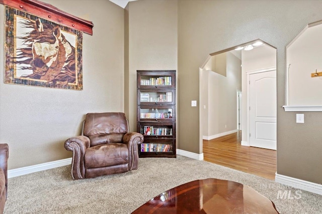 sitting room with arched walkways, carpet, and baseboards