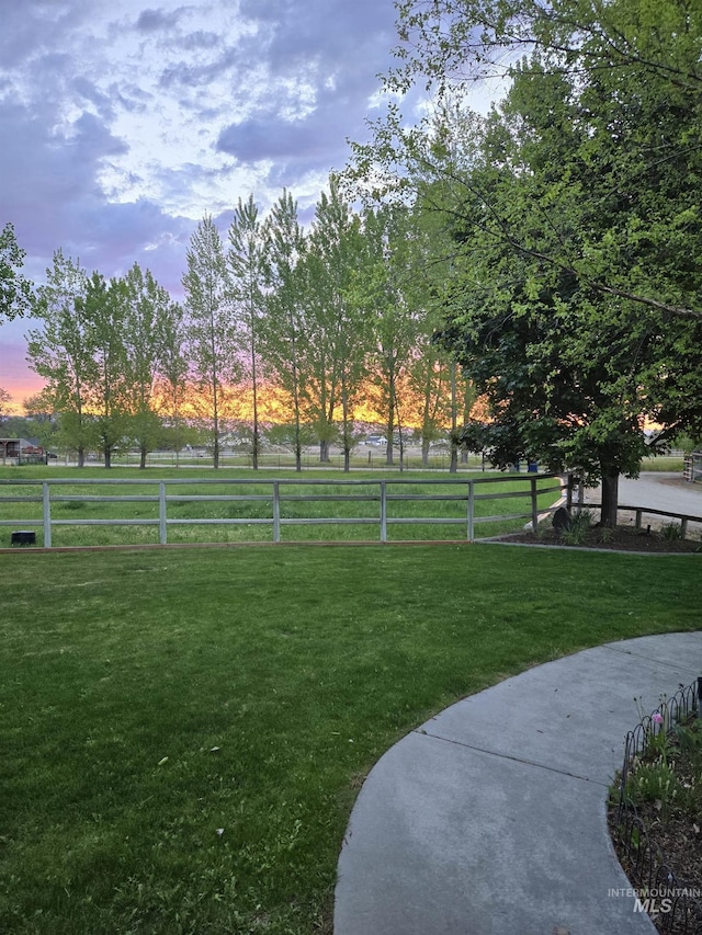 view of home's community featuring a rural view, fence, and a lawn