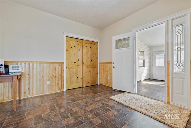 entryway featuring stone finish flooring, wainscoting, and wood walls