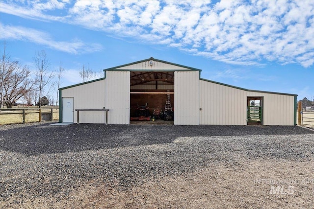 view of pole building featuring driveway and fence