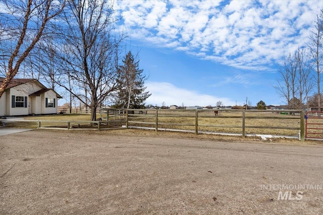 view of yard with a rural view, fence, and driveway