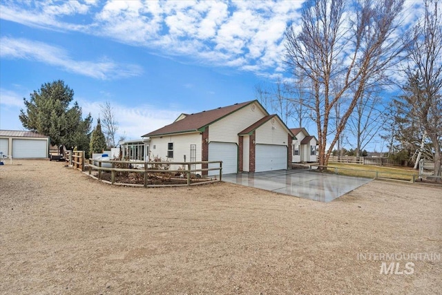 exterior space with a garage, driveway, an outdoor structure, and fence