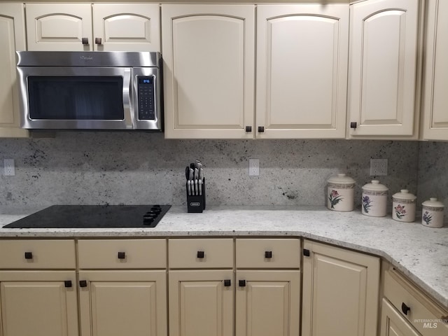 kitchen with black electric cooktop, backsplash, and light stone countertops