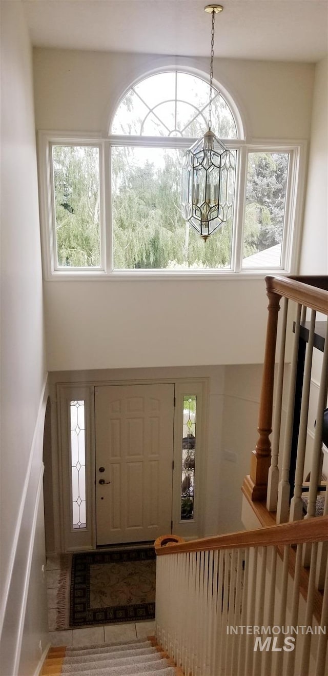 foyer featuring light tile patterned flooring, a chandelier, and a high ceiling