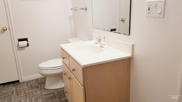 bathroom featuring vanity, parquet flooring, and toilet