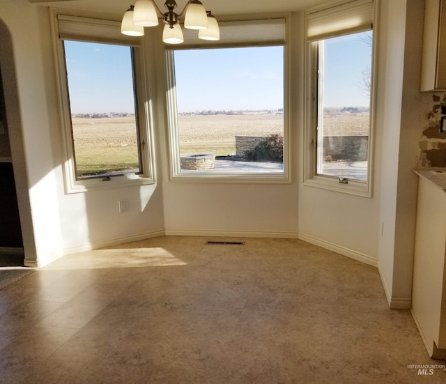 unfurnished dining area with plenty of natural light, a rural view, and a chandelier