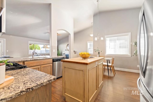 kitchen featuring a center island, vaulted ceiling, light hardwood / wood-style flooring, sink, and appliances with stainless steel finishes