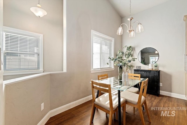 dining area featuring a chandelier, vaulted ceiling, and dark hardwood / wood-style floors