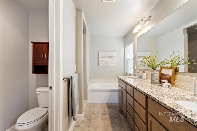 bathroom featuring vanity, a washtub, and toilet