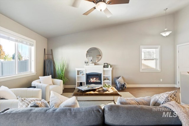 living room featuring a wealth of natural light, ceiling fan, light hardwood / wood-style flooring, and vaulted ceiling