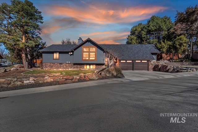 mid-century home with an attached garage, a chimney, and concrete driveway