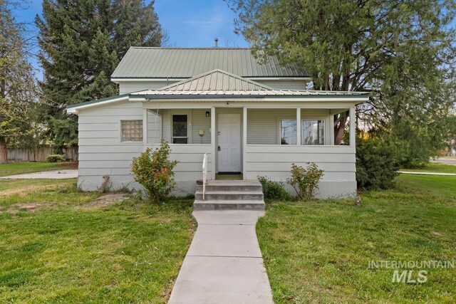 view of front of home with metal roof and a front lawn