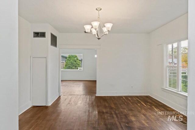 unfurnished dining area with a chandelier, visible vents, wood-type flooring, and baseboards