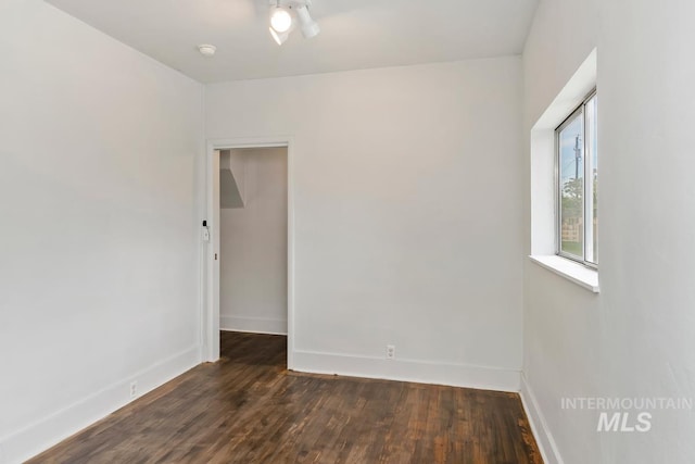 empty room with dark wood-style floors and baseboards