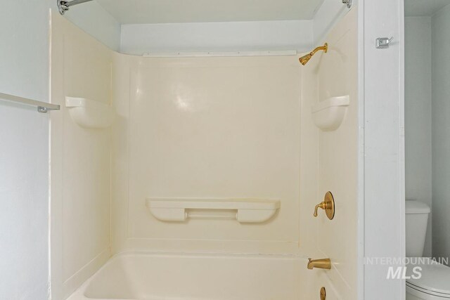bathroom with toilet and bathing tub / shower combination
