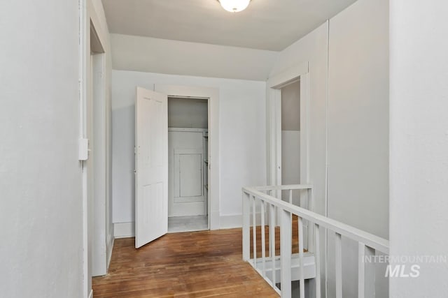 corridor featuring lofted ceiling, an upstairs landing, and wood finished floors