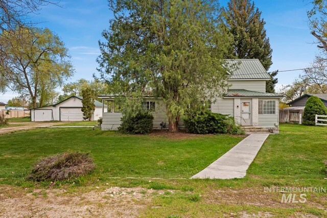 view of front of property featuring an outbuilding, a front lawn, metal roof, and a garage