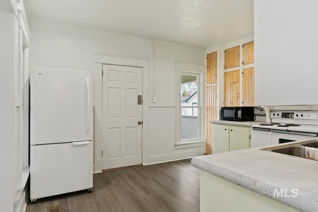 kitchen featuring dark wood finished floors, white appliances, light countertops, and a sink
