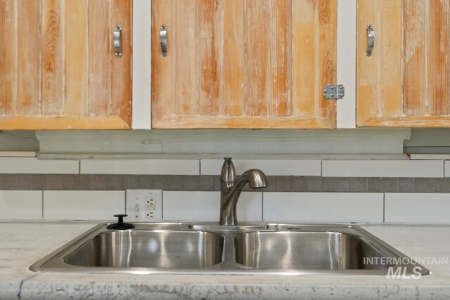 room details featuring tasteful backsplash, light stone countertops, and a sink