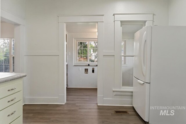 interior space with dark wood-style floors, light countertops, visible vents, baseboards, and freestanding refrigerator