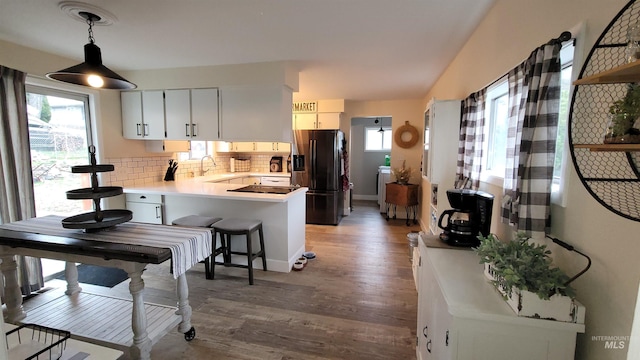 kitchen featuring a peninsula, fridge with ice dispenser, plenty of natural light, and a sink