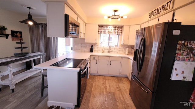 kitchen featuring fridge with ice dispenser, range with electric cooktop, light wood-style flooring, a sink, and stainless steel microwave